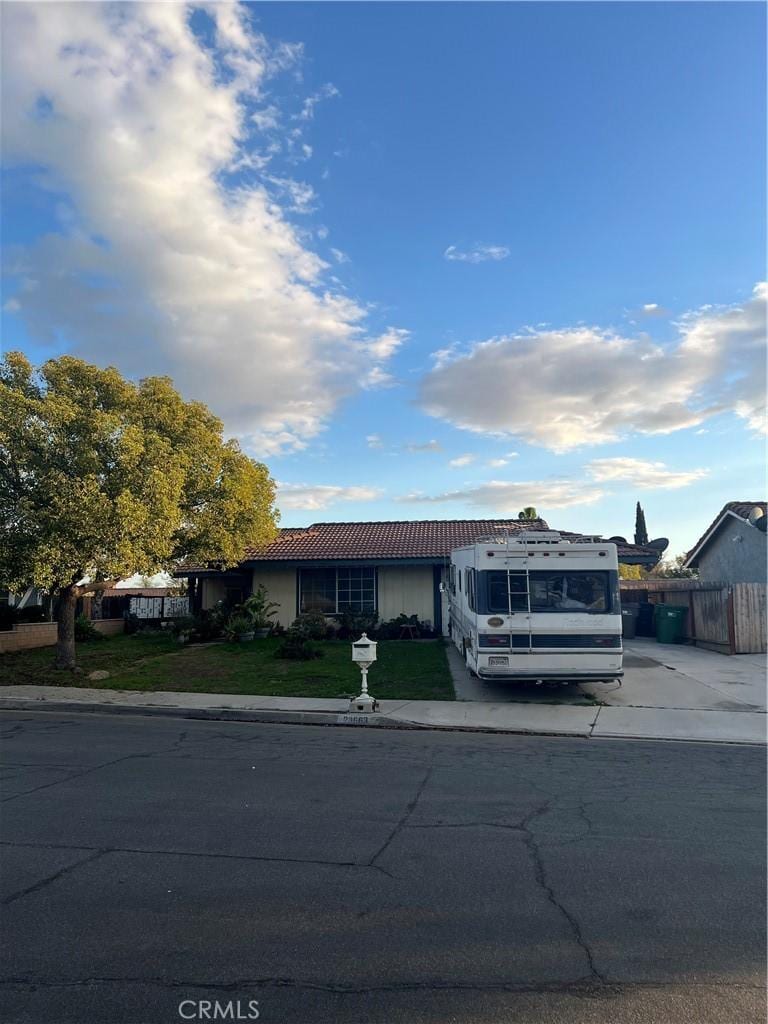 single story home with driveway, fence, a front lawn, and a tiled roof