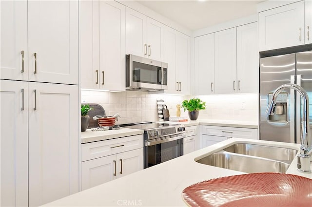 kitchen featuring stainless steel appliances, white cabinetry, and backsplash