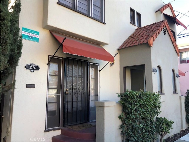 view of exterior entry featuring stucco siding and a tiled roof