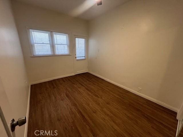 unfurnished room with dark wood-type flooring and baseboards