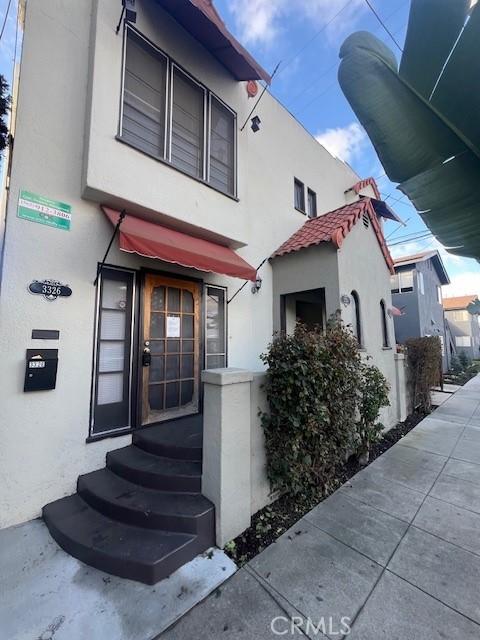 property entrance featuring a tile roof and stucco siding