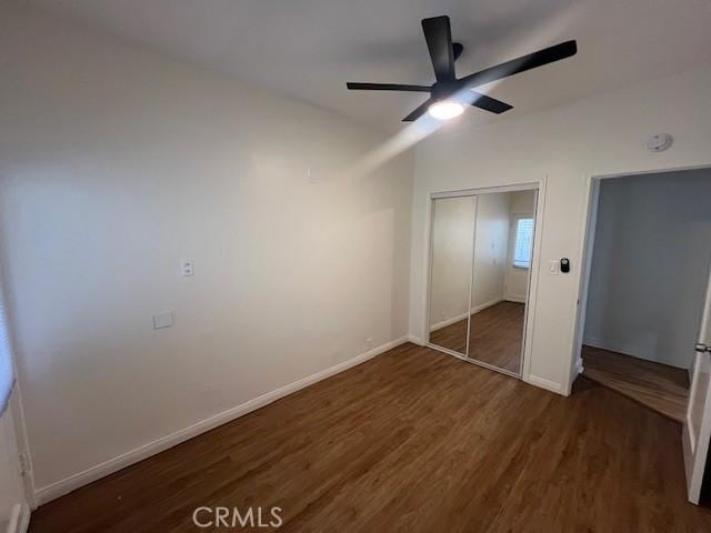 unfurnished bedroom featuring a closet, ceiling fan, baseboards, and wood finished floors