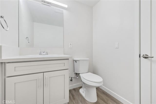 bathroom featuring baseboards, vanity, toilet, and wood finished floors