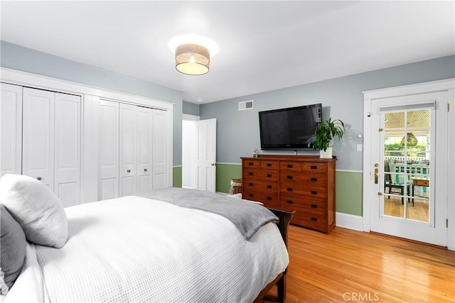 bedroom with light wood finished floors, visible vents, and a closet