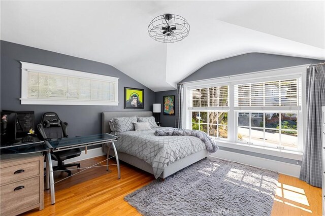 bedroom featuring baseboards, vaulted ceiling, and light wood-style flooring