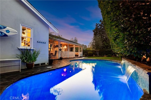 pool at dusk with a patio and an outdoor pool