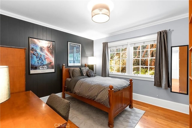 bedroom featuring baseboards, light wood-style flooring, and crown molding