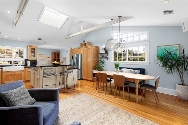 kitchen with stainless steel fridge with ice dispenser, dark countertops, a kitchen island, glass insert cabinets, and a sink