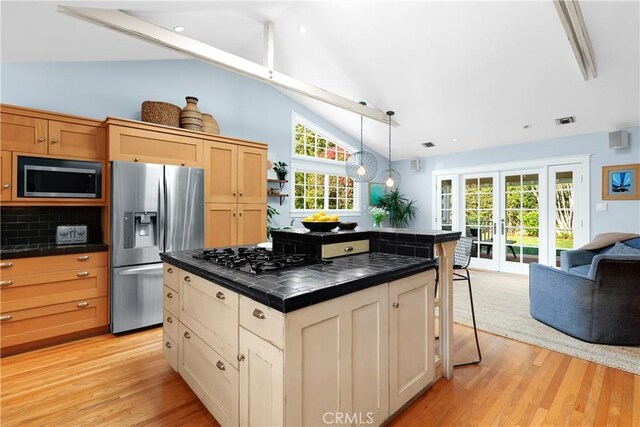 kitchen featuring light wood-type flooring, stainless steel appliances, tile countertops, and lofted ceiling