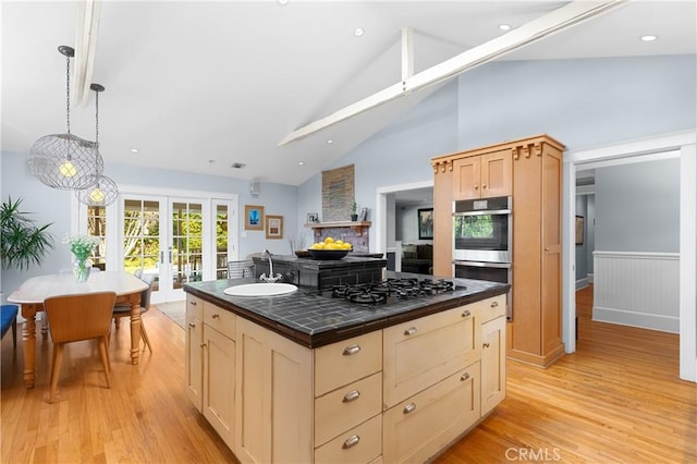 kitchen with black gas stovetop, stainless steel double oven, light wood-style floors, french doors, and tile counters