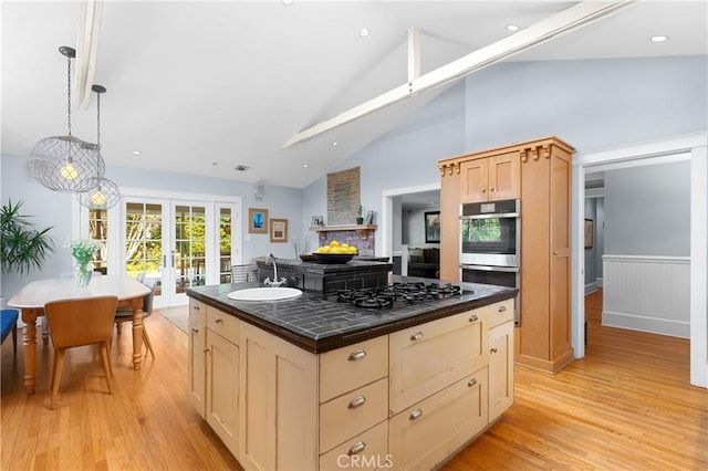 kitchen featuring double oven, light wood-style floors, french doors, a sink, and black gas stovetop