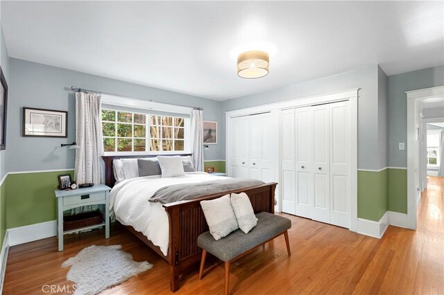 bedroom with baseboards, light wood finished floors, and multiple windows