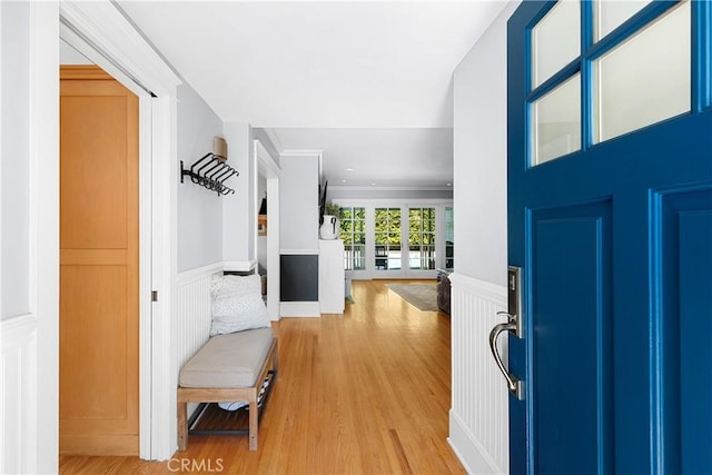 foyer featuring wainscoting, light wood-type flooring, and a decorative wall