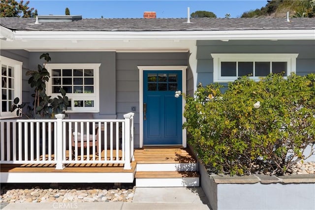 entrance to property with a porch and a chimney