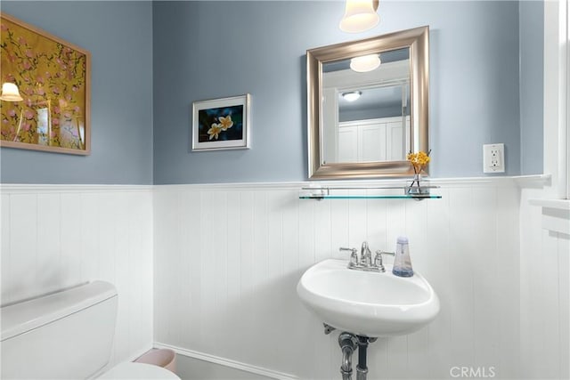 bathroom featuring a sink, a wainscoted wall, and toilet