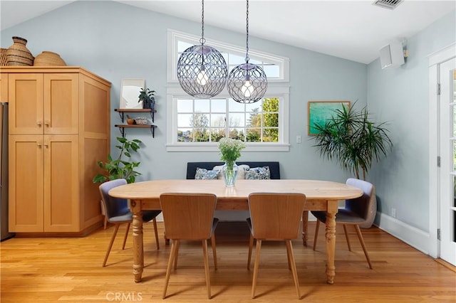 dining area with visible vents, baseboards, light wood-type flooring, a notable chandelier, and vaulted ceiling