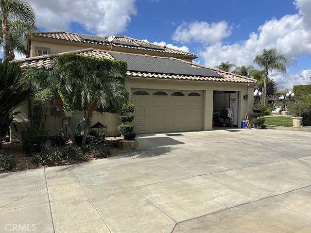 view of side of home with driveway, a garage, solar panels, a tiled roof, and stucco siding