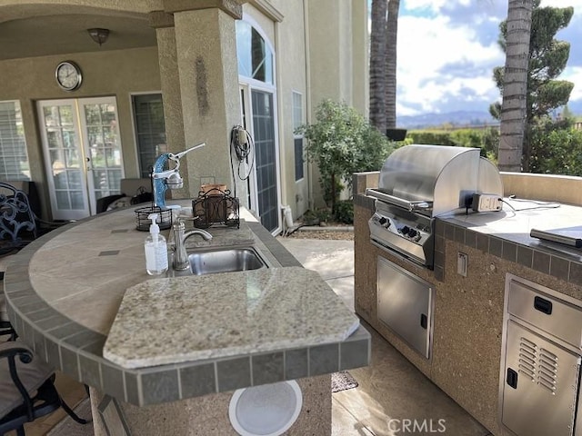 view of patio featuring french doors, exterior kitchen, outdoor dining space, and a grill