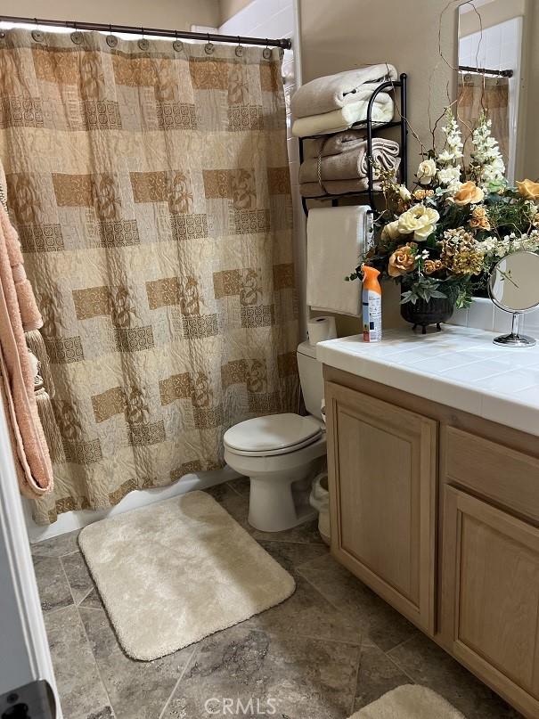 bathroom featuring curtained shower, vanity, and toilet