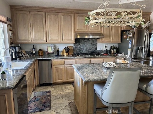 kitchen with a breakfast bar area, stone counters, a sink, ventilation hood, and appliances with stainless steel finishes