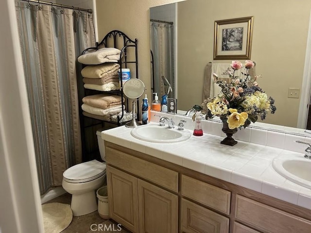 full bath with double vanity, toilet, and a sink