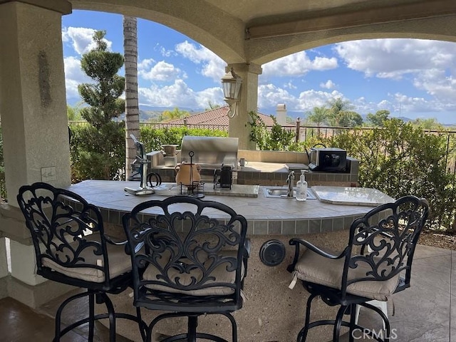 view of patio / terrace featuring a sink, an outdoor kitchen, a grill, and outdoor wet bar