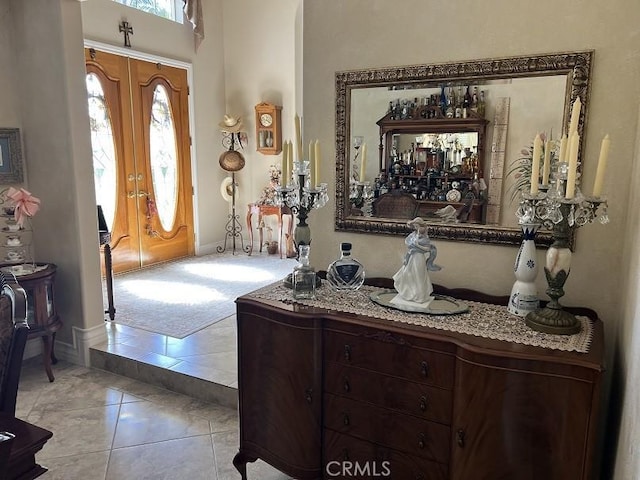 entrance foyer featuring french doors, plenty of natural light, light tile patterned flooring, and light colored carpet