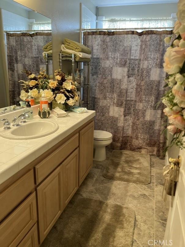 bathroom featuring curtained shower, vanity, and toilet