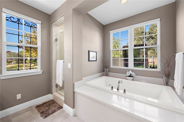 bathroom featuring a shower stall, baseboards, a bath, and tile patterned floors