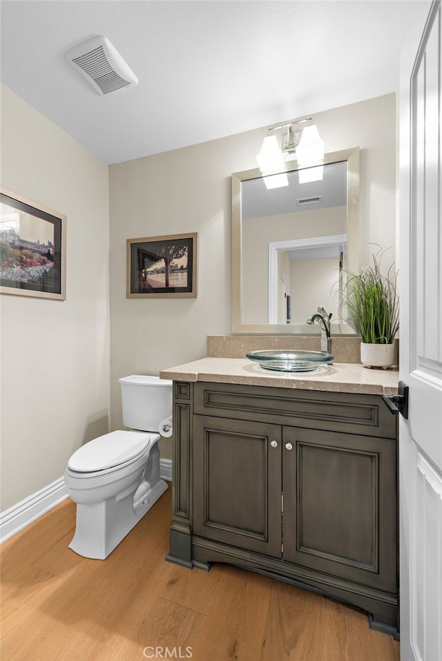 bathroom with visible vents, vanity, toilet, and wood finished floors