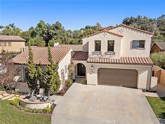 mediterranean / spanish house with concrete driveway, a tiled roof, an attached garage, and stucco siding