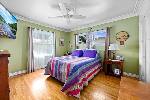 bedroom with baseboards, light wood finished floors, a ceiling fan, and crown molding