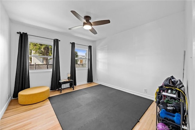 workout room featuring ceiling fan, wood finished floors, and baseboards