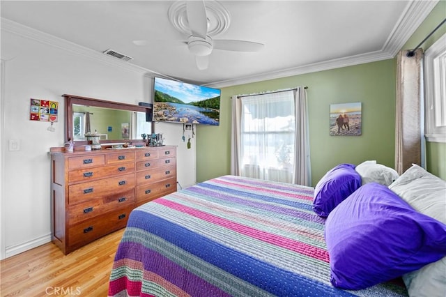 bedroom featuring baseboards, visible vents, a ceiling fan, wood finished floors, and crown molding