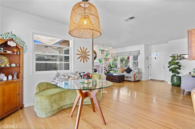 dining area with an inviting chandelier, light wood-style flooring, and visible vents