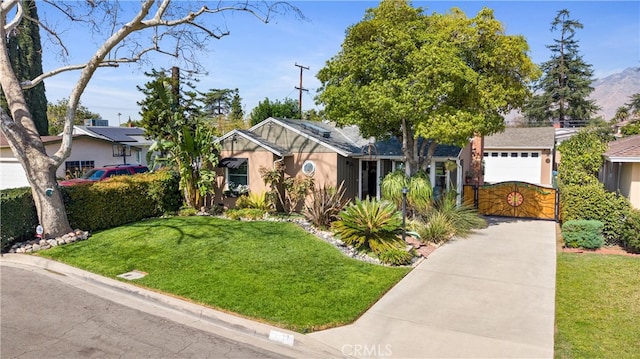 view of front facade with a garage, a front yard, a gate, and stucco siding