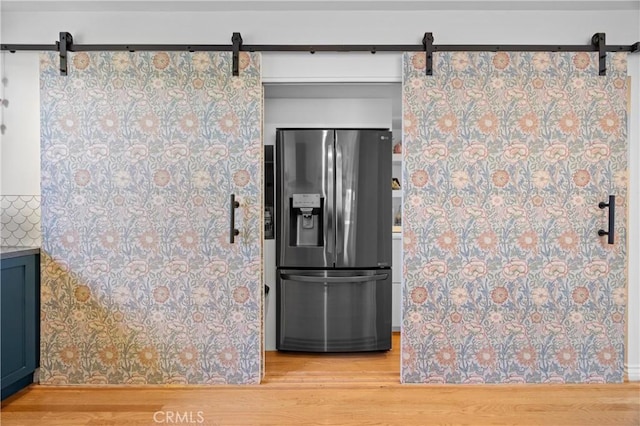 kitchen featuring a barn door, wood finished floors, and stainless steel fridge with ice dispenser