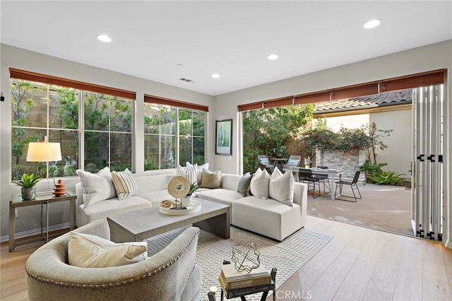 living room with light wood-style flooring, visible vents, and recessed lighting