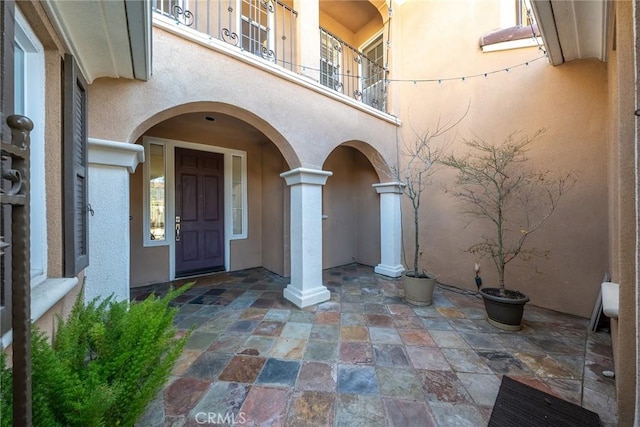 doorway to property featuring a patio, a balcony, and stucco siding