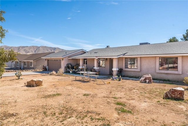 rear view of property featuring a garage, a mountain view, and stucco siding