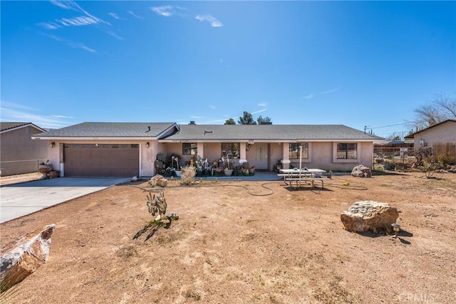 ranch-style home with a garage, concrete driveway, and stucco siding