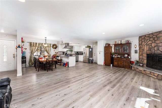 living room featuring recessed lighting, a fireplace, and light wood-style flooring