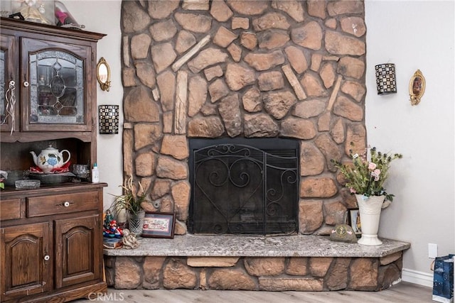 room details featuring a fireplace, baseboards, and wood finished floors