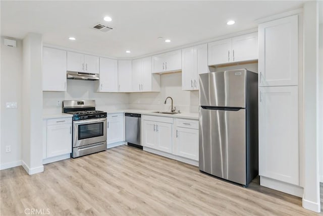 kitchen with light countertops, appliances with stainless steel finishes, white cabinetry, a sink, and under cabinet range hood