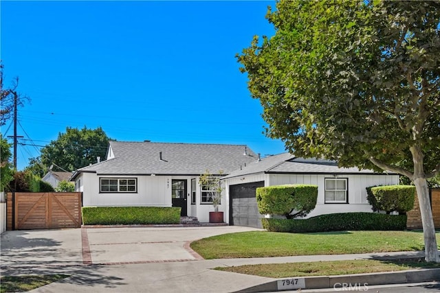 view of front of home featuring concrete driveway, a front yard, a gate, fence, and a garage