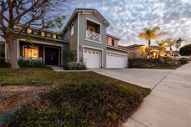 view of front of house featuring driveway, a front lawn, an attached garage, and a balcony