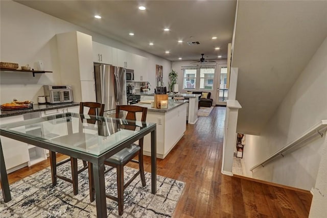 kitchen featuring visible vents, a kitchen island, appliances with stainless steel finishes, dark wood-style flooring, and white cabinetry