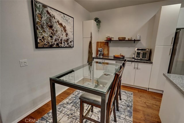 dining space with light wood-type flooring and baseboards