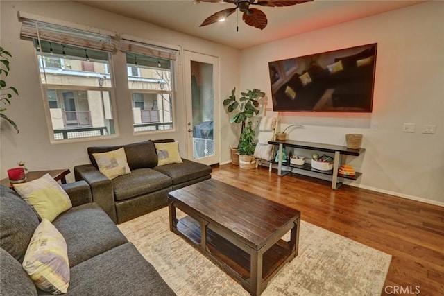 living room featuring a ceiling fan, baseboards, and wood finished floors