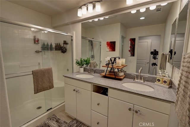 bathroom with a stall shower, visible vents, a sink, and double vanity